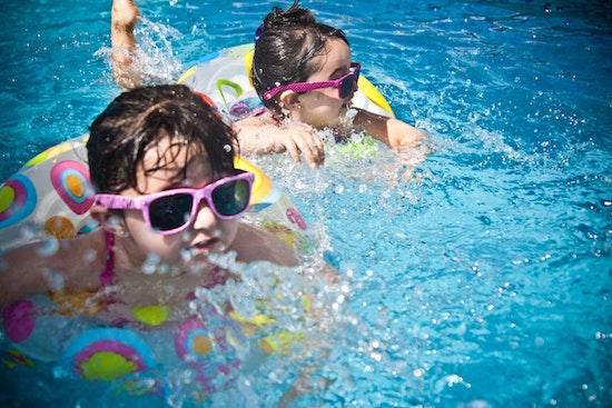 孩子们在游泳池游泳与最好的太阳能游泳池加热器加热”class=